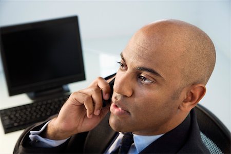 simsearch:400-04186486,k - African American businessman sitting at office desk on cellphone. Stock Photo - Budget Royalty-Free & Subscription, Code: 400-04186192
