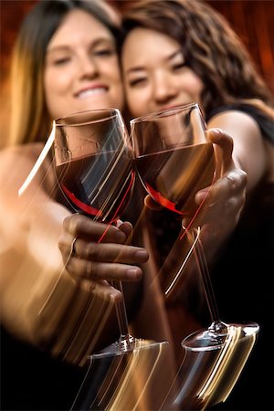 Two attractive young women toasting wine glasses with red wine and smiling. Stock Photo - Budget Royalty-Free & Subscription, Code: 400-04186333