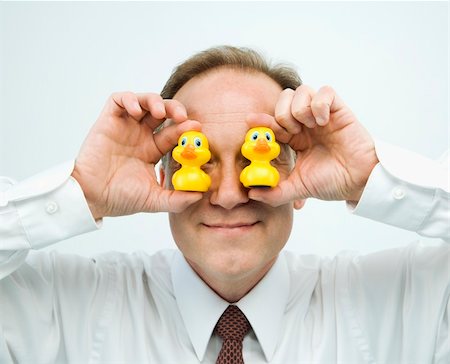 Portrait of middle aged  Caucasian businessman holding rubber ducks up to face. Foto de stock - Super Valor sin royalties y Suscripción, Código: 400-04186450