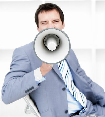 simsearch:400-06763387,k - Furious young businessman yelling through a megaphone sitting on his desk Stock Photo - Budget Royalty-Free & Subscription, Code: 400-04186950