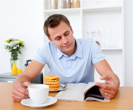 simsearch:400-04687391,k - Smiling man reading a newspaper while having breakfast in the kitchen Stock Photo - Budget Royalty-Free & Subscription, Code: 400-04188240