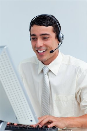 simsearch:400-04352175,k - Cheerful businessman using headset working at a computer Stock Photo - Budget Royalty-Free & Subscription, Code: 400-04188455