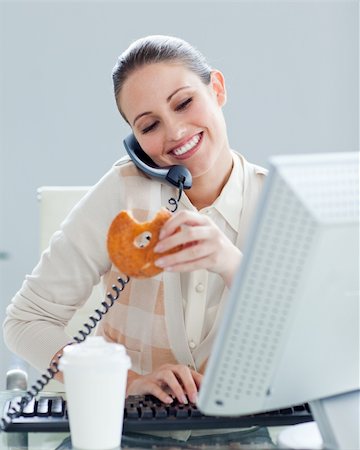 simsearch:400-04341796,k - Confident businesswoman on phone eating a donnut in the office Stockbilder - Microstock & Abonnement, Bildnummer: 400-04188633