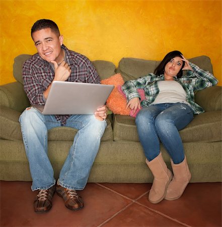 Bored Hispanic woman reacting to man with computer on green couch Stock Photo - Budget Royalty-Free & Subscription, Code: 400-04188824