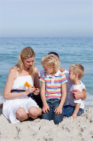 family beach sun protection - Attentive mother holding sunscreen at the beach with her family Stock Photo - Budget Royalty-Free & Subscription, Code: 400-04188969