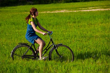 simsearch:400-04201795,k - Happy young woman on a green meadow riding a bicycle Fotografie stock - Microstock e Abbonamento, Codice: 400-04181988