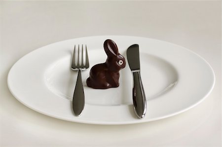 Chocolate Easter bunny sitting on a white plate surrounded by a fork and a knife. Photographie de stock - Aubaine LD & Abonnement, Code: 400-04182070