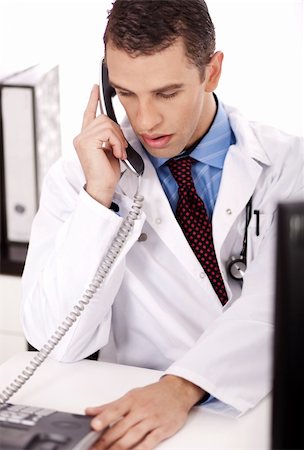 young physician sitting at his desk talking over phone in white background Stock Photo - Budget Royalty-Free & Subscription, Code: 400-04182760