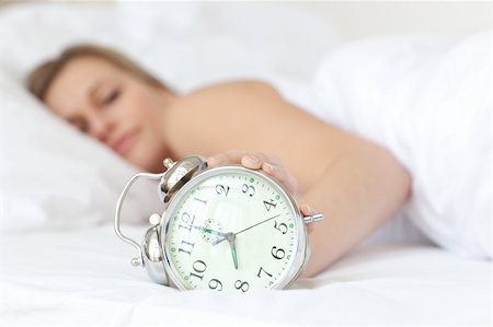 simsearch:700-03554506,k - Young woman holding an alarm clock and sleeping on her bed Stockbilder - Microstock & Abonnement, Bildnummer: 400-04182846