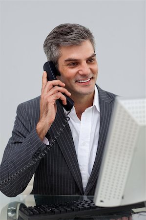 simsearch:400-04782151,k - Positive male executive talking on phone at his desk Photographie de stock - Aubaine LD & Abonnement, Code: 400-04183252