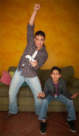 simsearch:400-04173797,k - Handsome Hispanic man playing Video game with bored young boy Stock Photo - Budget Royalty-Free & Subscription, Code: 400-04194110