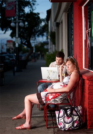 Pregnant woman sitting outside with annoying partner on computer next to her Stock Photo - Budget Royalty-Free & Subscription, Code: 400-04194260