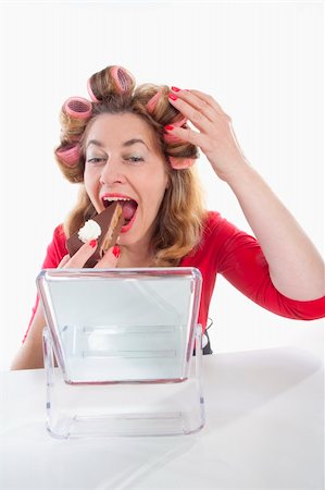 middle-aged woman with hair rollers eating cake looking at mirror Stock Photo - Budget Royalty-Free & Subscription, Code: 400-04194892