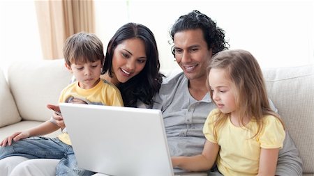 Affectionate parents using laptop with their children on sofa Stock Photo - Budget Royalty-Free & Subscription, Code: 400-04195278