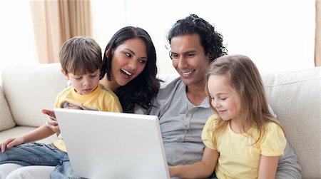 simsearch:400-04575374,k - Happy family using laptop on sofa in the living room Stock Photo - Budget Royalty-Free & Subscription, Code: 400-04195279