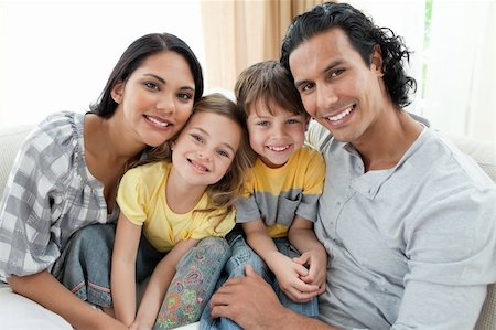 simsearch:400-04192370,k - Portrait of a smiling family sitting on sofa at home Fotografie stock - Microstock e Abbonamento, Codice: 400-04195284