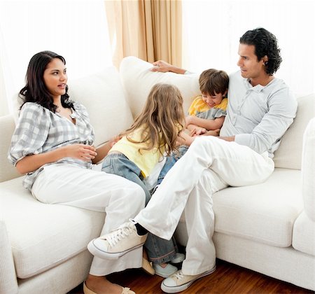 simsearch:400-04192370,k - Attentive parents sitting on sofa with their children at home Fotografie stock - Microstock e Abbonamento, Codice: 400-04195285
