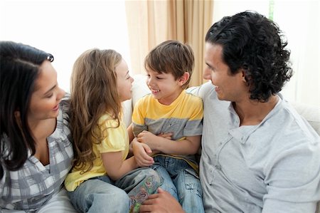 simsearch:400-04192370,k - Cute siblings sitting on sofa with their parents at home Fotografie stock - Microstock e Abbonamento, Codice: 400-04195288