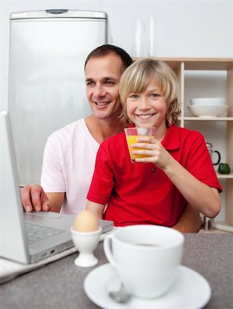 family eating computer - Smiling father and his son having breakfast in the kitchen Stock Photo - Budget Royalty-Free & Subscription, Code: 400-04195677