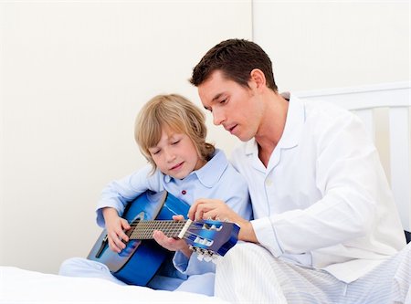 Cute little boy playing guitar with his father in the bedroom Stock Photo - Budget Royalty-Free & Subscription, Code: 400-04195899