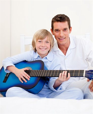 Merry little boy playing guitar with his father in the bedroom Stock Photo - Budget Royalty-Free & Subscription, Code: 400-04195892