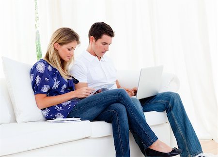 simsearch:400-07955632,k - Young couple working at home sitting on sofa Photographie de stock - Aubaine LD & Abonnement, Code: 400-04195945