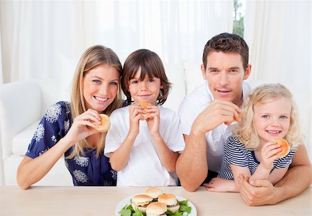 family eating burgers - Smiling family eating burgers in the living room at home Stock Photo - Budget Royalty-Free & Subscription, Code: 400-04195986