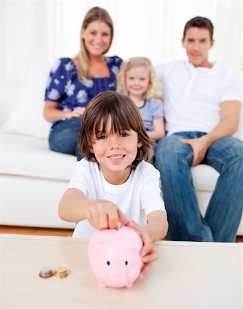 Cheerful little boy inserting coin in a piggybank in the living room Stock Photo - Budget Royalty-Free & Subscription, Code: 400-04195998
