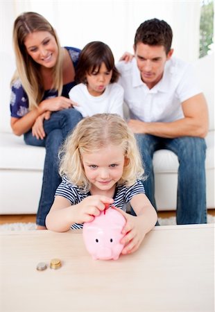 Adorable little girl inserting coin in a piggybank in the living room Stock Photo - Budget Royalty-Free & Subscription, Code: 400-04196001