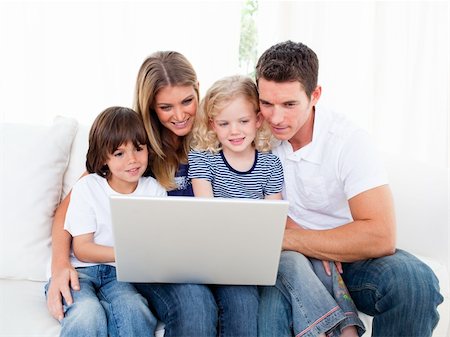 Portrait of a jolly family using a laptop sitting on sofa at home Stock Photo - Budget Royalty-Free & Subscription, Code: 400-04196003