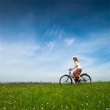 simsearch:400-04201795,k - Happy young woman on a green meadow riding a bicycle Fotografie stock - Microstock e Abbonamento, Codice: 400-04196134