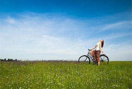 simsearch:400-04201795,k - Happy young woman with a vintage bicycle on a green meadow Fotografie stock - Microstock e Abbonamento, Codice: 400-04196130