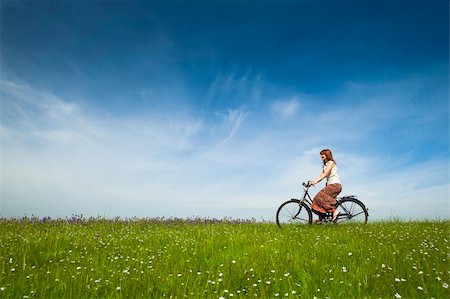 simsearch:400-04201795,k - Happy young woman on a green meadow riding a bicycle Fotografie stock - Microstock e Abbonamento, Codice: 400-04196133