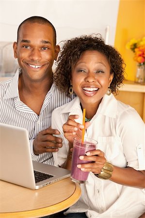 drinking milk shake - Young couple smile as they work on a laptop.  The woman is holding a smoothie.  Vertical shot. Stock Photo - Budget Royalty-Free & Subscription, Code: 400-04196311