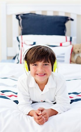 simsearch:400-04152181,k - Smiling little boy listening music with headphones on lying on his bed Stock Photo - Budget Royalty-Free & Subscription, Code: 400-04196929