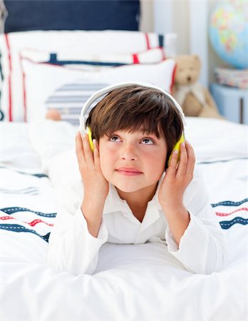 simsearch:400-04152181,k - Cute little boy listening music with headphones on lying on his bed Stock Photo - Budget Royalty-Free & Subscription, Code: 400-04196931