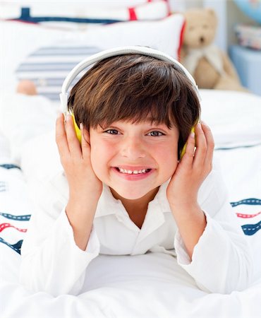 simsearch:400-04152181,k - Happy little boy listening music with headphones on lying on his bed Stock Photo - Budget Royalty-Free & Subscription, Code: 400-04196933