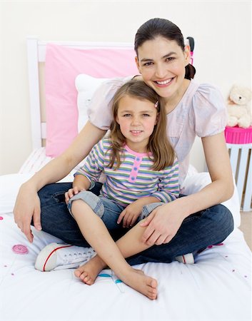 simsearch:400-05749479,k - Smiling mother hugging her girl sitting on a bed Foto de stock - Royalty-Free Super Valor e Assinatura, Número: 400-04196942