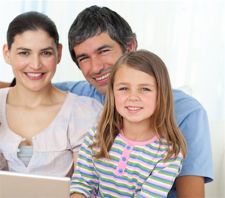 Little girl using a laptop with her parents on the sofa Stock Photo - Budget Royalty-Free & Subscription, Code: 400-04196968