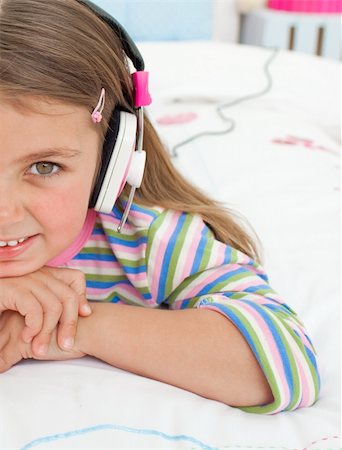 simsearch:400-05717354,k - Little gril listening to music with headphones lying on her bed Stock Photo - Budget Royalty-Free & Subscription, Code: 400-04196981