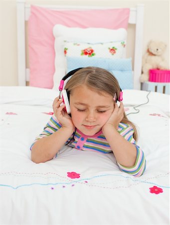 simsearch:400-05717354,k - Beautiful Little gril listening to music with headphones lying on her bed Stock Photo - Budget Royalty-Free & Subscription, Code: 400-04196982