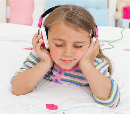 simsearch:400-05717354,k - Close-up of a Little gril listening to music with headphones lying on her bed Stock Photo - Budget Royalty-Free & Subscription, Code: 400-04196983