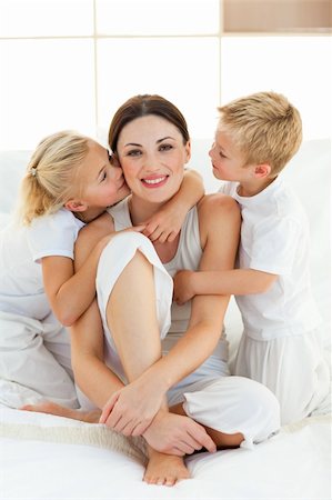 simsearch:400-05749479,k - Beautiful children kissing their mother sitting on a bed Foto de stock - Royalty-Free Super Valor e Assinatura, Número: 400-04197275