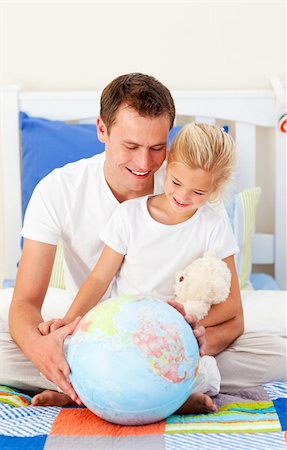 Earing father and his daugther looking at a terrestrial globe sitting on bed Stock Photo - Budget Royalty-Free & Subscription, Code: 400-04197344