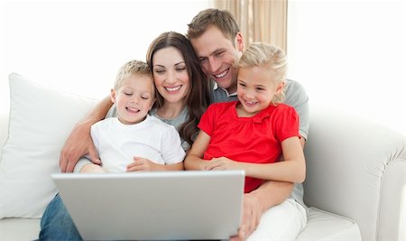 Joyful family using a computer sitting on sofa in the living room Stock Photo - Budget Royalty-Free & Subscription, Code: 400-04197549