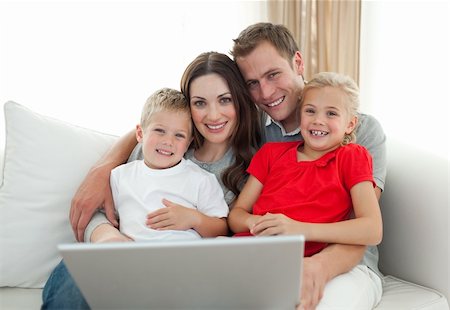 Jolly family using a computer sitting on sofa in the living room Stock Photo - Budget Royalty-Free & Subscription, Code: 400-04197550