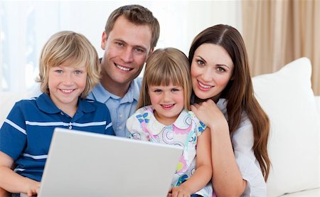 Jolly family using a laptop sitting on sofa at home Stock Photo - Budget Royalty-Free & Subscription, Code: 400-04197552