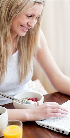 simsearch:400-04708507,k - Cheerful woman using a laptop while having a breakfast in a living-room Stock Photo - Budget Royalty-Free & Subscription, Code: 400-04198679