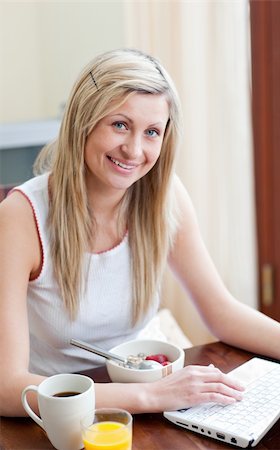 simsearch:400-04708507,k - Charming woman using a laptop while having a breakfast in a living-room Stock Photo - Budget Royalty-Free & Subscription, Code: 400-04198680