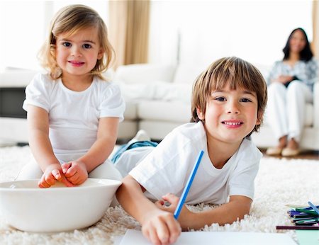 Cheerful siblings eating chips and drawing lying on the floor Photographie de stock - Aubaine LD & Abonnement, Code: 400-04198764